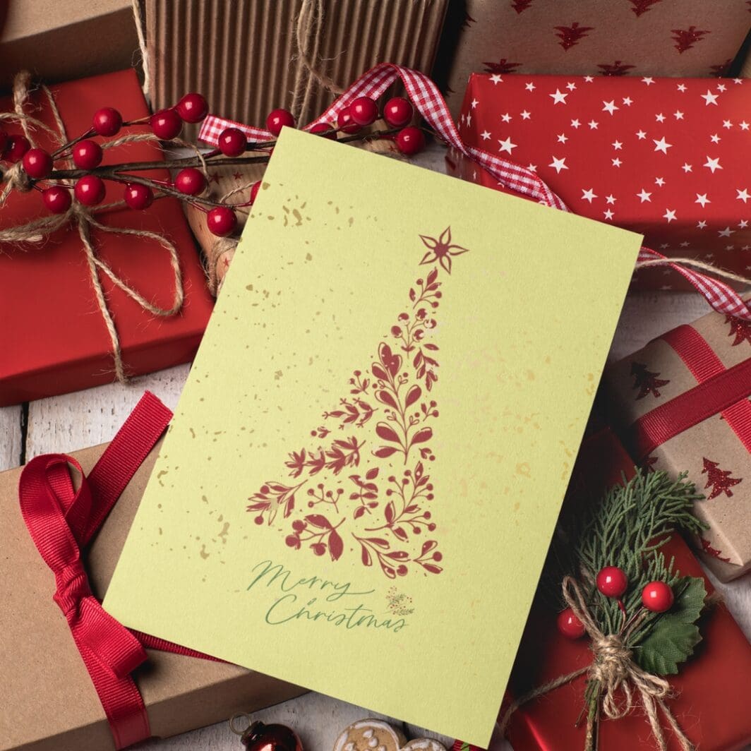 Elegant Christmas greeting card with a minimalist red floral tree design on a soft yellow background, topped with a star, and 'Merry Christmas' written in green script at the bottom.