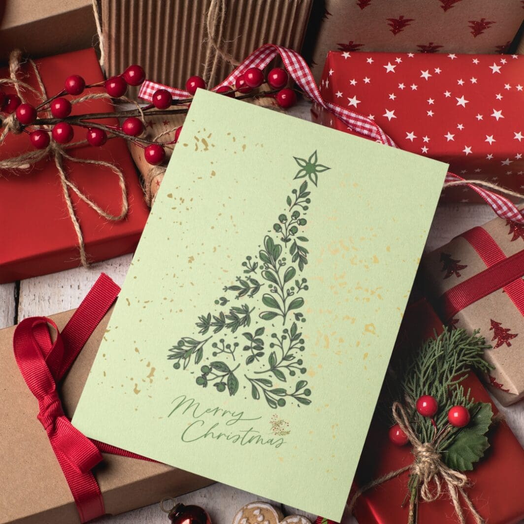 Elegant Christmas greeting card with a minimalist red floral tree design on a soft yellow background, topped with a star, and 'Merry Christmas' written in green script at the bottom.